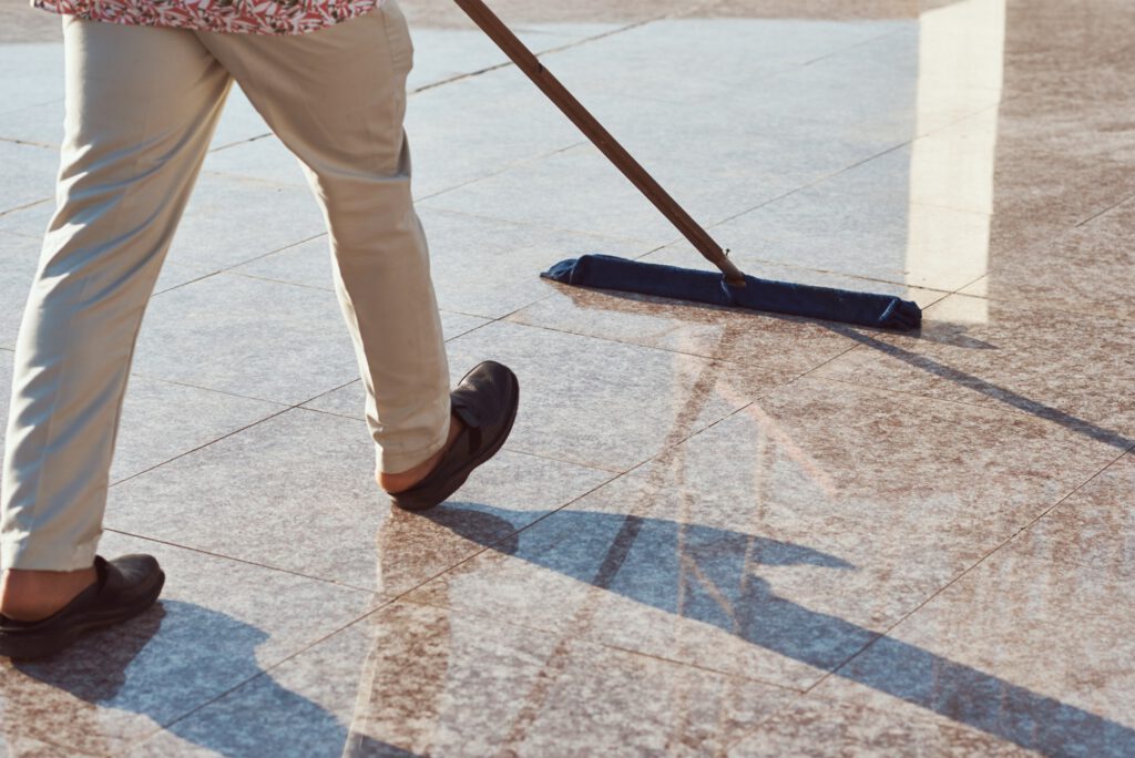 Cleaner with a mop cleaning marble floor outdoors. Cleaning service