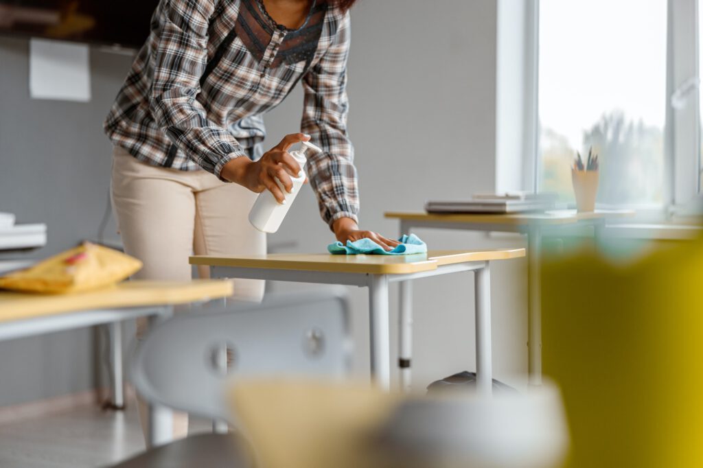 Teacher using a disinfector in school during coronavirus epidemic